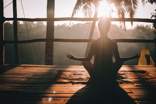 a woman sitting meditating at sunrise